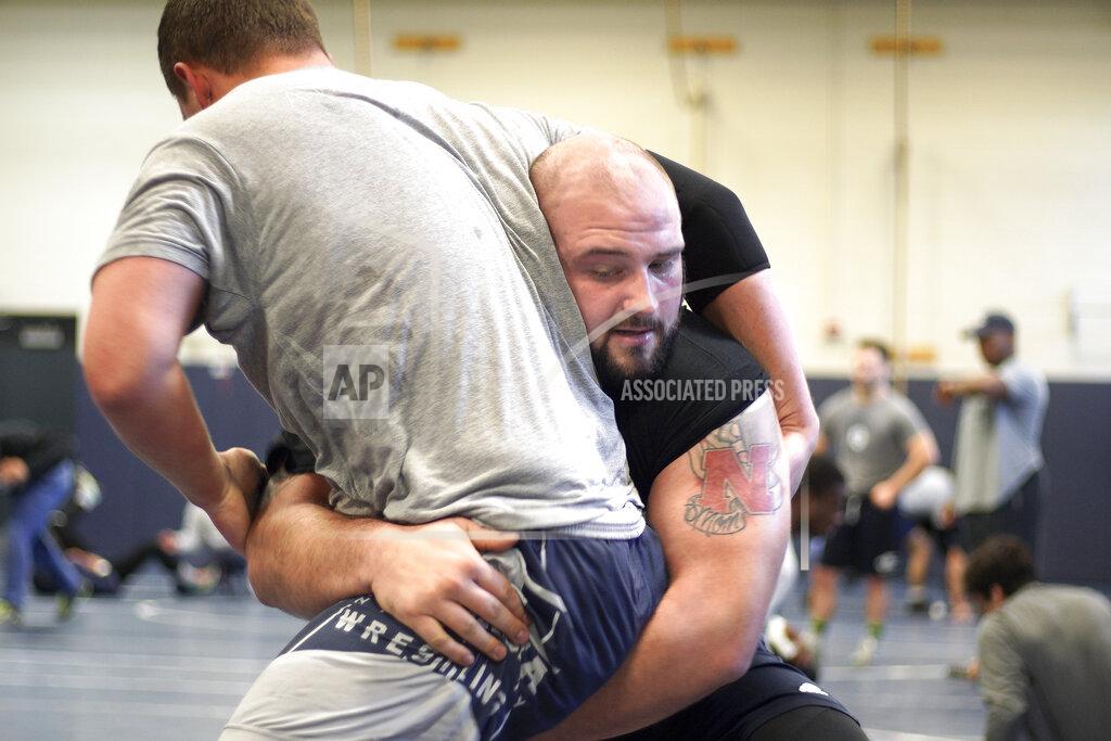 Nati Harnik In this March 2, 2020, photo, former Nebraska football player Tanner Farmer and current wrestler for Concordia University sports a Nebraska N tattoo on his left bicep as he practices in Seward, Neb. A year ago Farmer was thought to be on the rise as an NFL draft prospect. He had started three years on Nebraska's offensive line and turned in a stellar performance at the Cornhuskers' pro day. It turned out he went undrafted, so he took a volunteer assistant's job with the Concordia football team and then, quite by accident, discovered he had one semester of eligibility to compete in another sport in the National Association of Intercollegiate Athletics. He chose wrestling. (AP Photo/Nati Harnik)