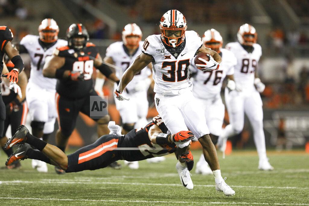 CORRECTS TO CHUBA HUBBARD, INSTEAD OF GABE SIMPSON - Oklahoma State running back Chuba Hubbard (30) is brought down by Oregon State defensive back David Morris (24) during the first half of an NCAA college football game in Corvallis, Ore., Friday, Aug. 30, 2019. (AP Photo/Amanda Loman)