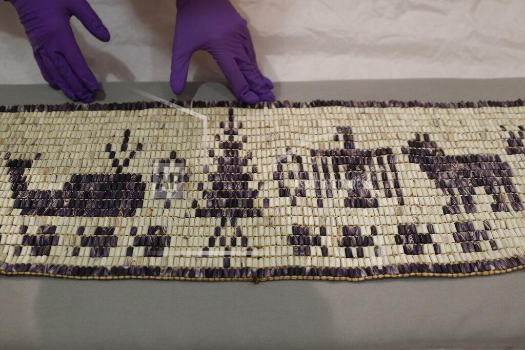 Alastair Grant Co-curator Jo Loosemore examines a recently created wampum belt made by members of the Wampanoag Native America people, after its unpacking and prior to it going on display in Southampton, England, Thursday, Aug. 13, 2020. On the 400th anniversary of the Mayflower voyage, commemorations are focusing on both the Pilgrim settlers and the Native people whose lives were transformed by their arrival. An exhibition in England focuses on one casualty of colonization: a wampum belt taken from the Wampanoag people to England in the 17th century, and then lost. (AP Photo/Alastair Grant)