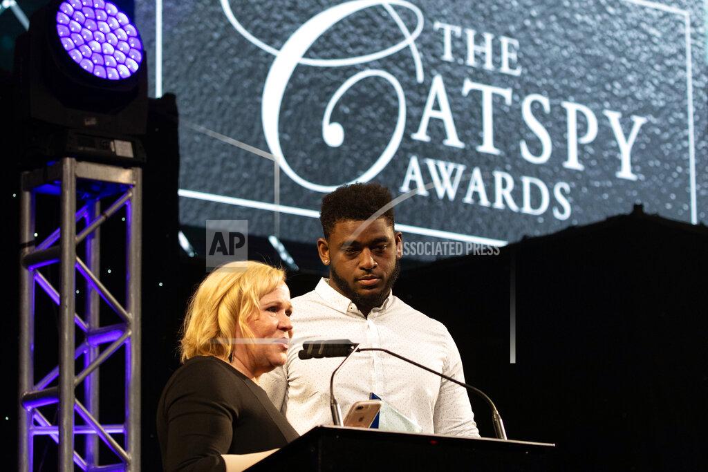 Mark Mahan FILE - In this April 19, 2019, photo, ESPN's Holly Rowe presents Kentucky NCAA college football player Josh Paschal with the Heart of a Wildcat at the University's annual CATSPY Awards at Memorial Coliseum in Lexington, Ky. Paschal is a cancer survivor, having completed treatment in August, about a year after what he thought was a blister on the bottom of his foot turned out to be a malignant melanoma. Paschal is one of 30 nominees for the Mayo Clinic Comeback Player of the Year Award. (Mark Mahan/Lexington Herald-Leader via AP)
