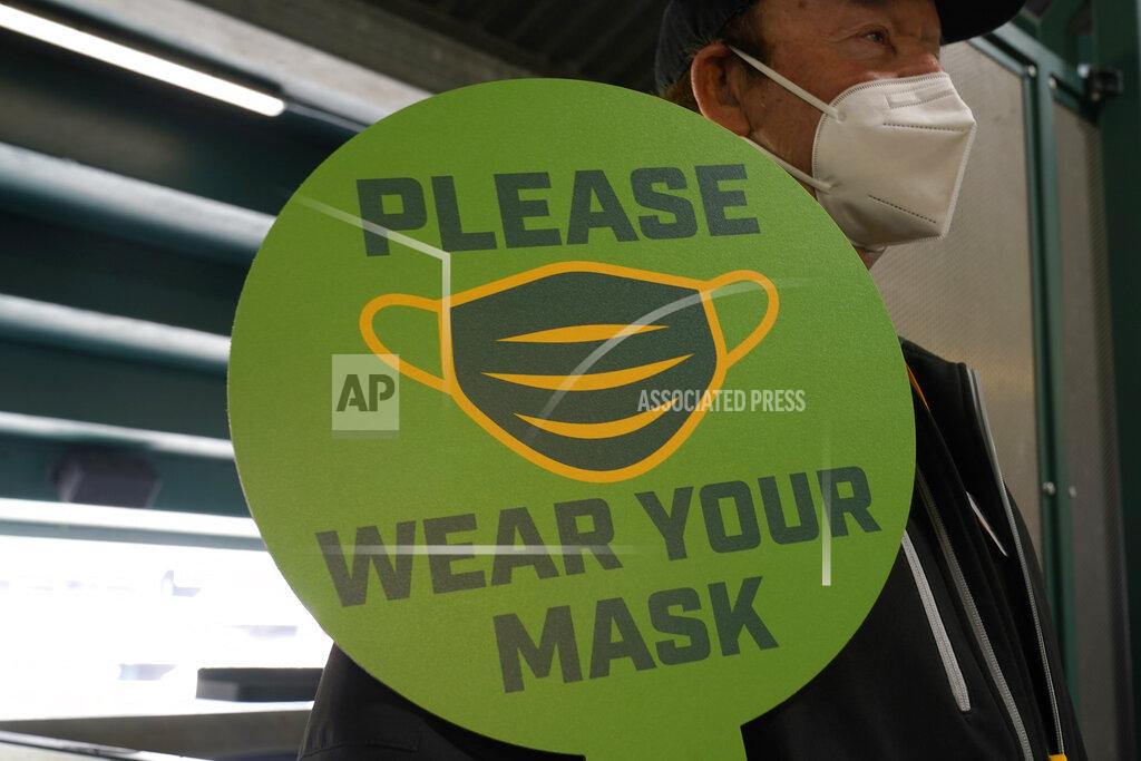 Jeff Chiu FILE - In this April 3, 2021, file photo, a stadium worker holds up a sign for people to wear face masks before a baseball game between the Oakland Athletics and the Houston Astros in Oakland, Calif. California is keeping its rules for wearing facemasks in place until the state more broadly lifts its pandemic restrictions on June 15. State officials said Monday, May 17 that the delay will give people time to prepare, and for the state to make sure that virus cases stay low. (AP Photo/Jeff Chiu, File)