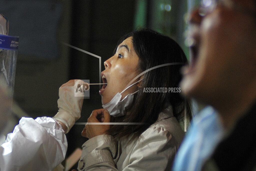 Uncredited A medical staff takes a swab from a woman as residents receive the COVID-19 test near the residential area in Qingdao in east China's Shandong province on Tuesday, Oct. 13, 2020. A hospital president and the director of the health commission in the northern Chinese city of Qingdao have been fired after China's latest coronavirus outbreak, authorities said Thursday, Oct. 15, 2020. (Chinatopix via AP)