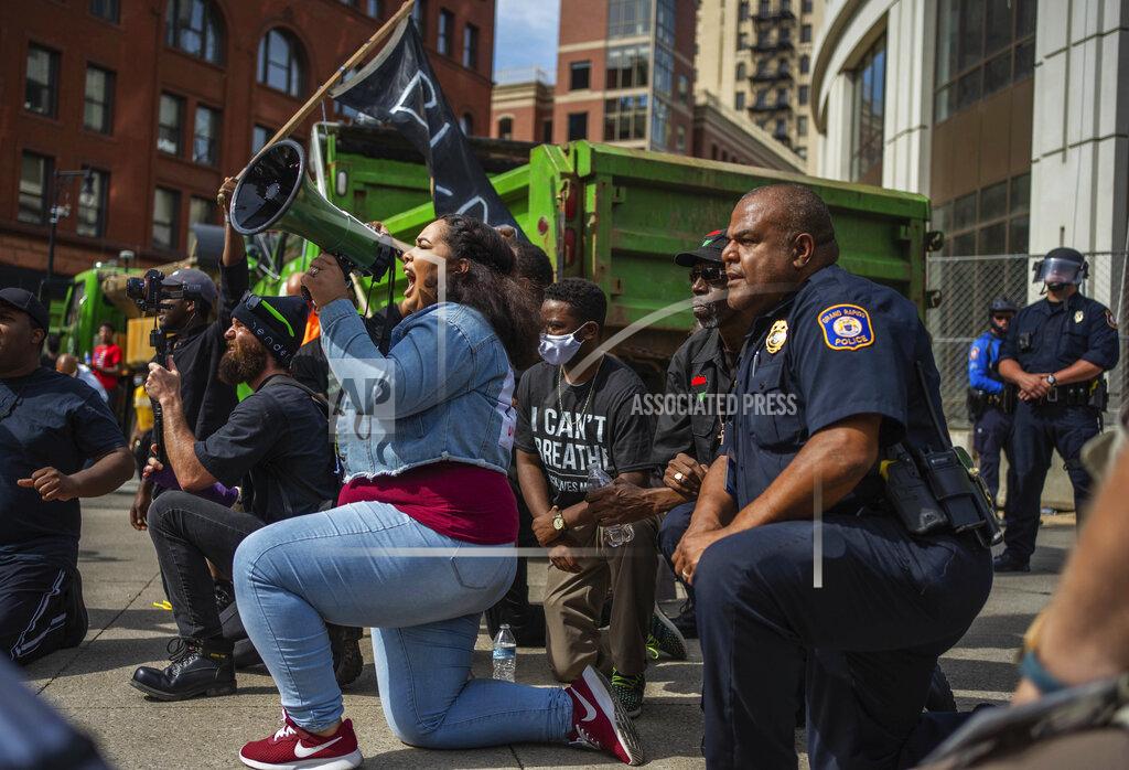 Protest organizer Alyssa Bates, left, kneels beside Grand Rapids police Chief Eric Payne during a protest in downtown Grand Rapids, Mich., Wednesday, June 3, 2020, prompted by the death of George Floyd. (Anntaninna Biondo/The Grand Rapids Press via AP)