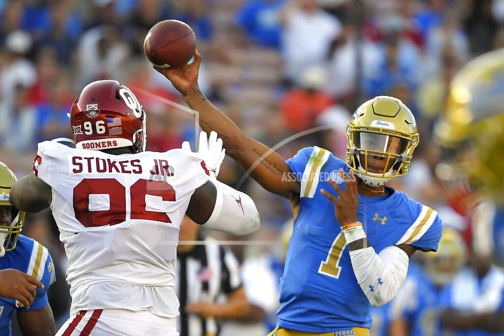 Mark J. Terrill UCLA quarterback Dorian Thompson-Robinson, right, passes while under pressure from Oklahoma defensive lineman LaRon Stokes during the first half of an NCAA college football game Saturday, Sept. 14, 2019, in Pasadena, Calif. (AP Photo/Mark J. Terrill)