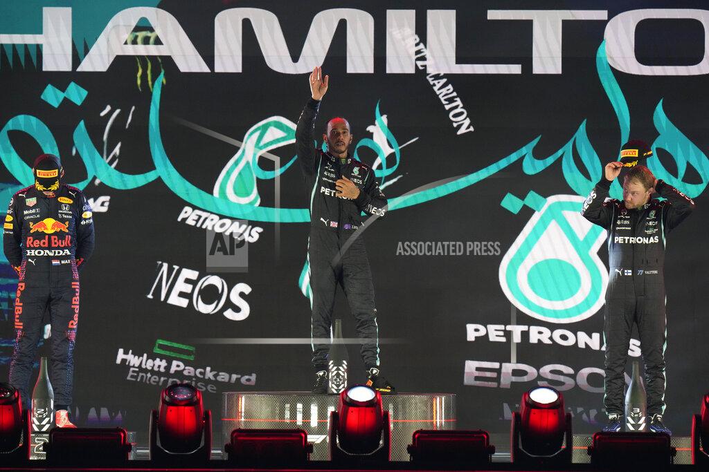 Hassan Ammar Mercedes driver Lewis Hamilton of Britain waves from the podium after winning the Formula One Saudi Arabian Grand Prix in Jiddah, Sunday, Dec. 5, 2021. Left is second placed Red Bull driver Max Verstappen of the Netherlands and Ron the right is third, Mercedes driver Valtteri Bottas of Finland. (AP Photo/Hassan Ammar)