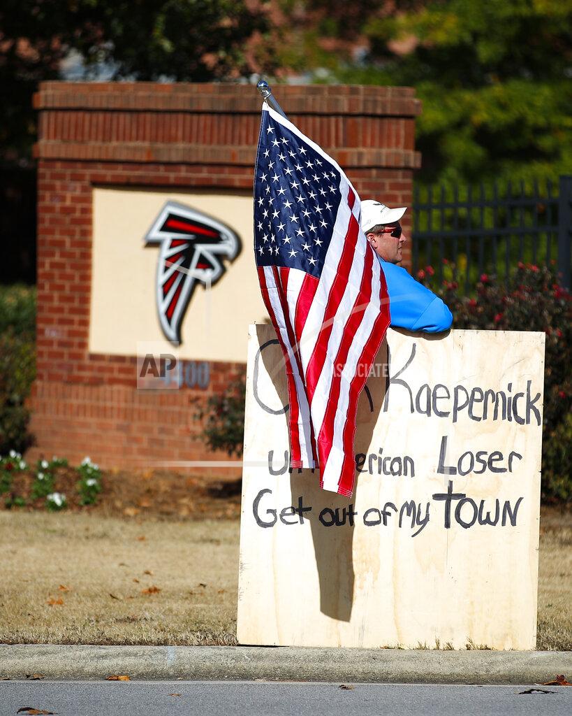 Todd Kirkland A protester holds an American flag and a sign outside of the Atlanta Falcons' training facility where free agent quarterback Colin Kaepernick was set to workout for NFL football scouts, Saturday, Nov. 16, 2019, in Flowery Branch, Ga. The workout was moved to a high school in Riverdale, Ga. (AP Photo/Todd Kirkland)