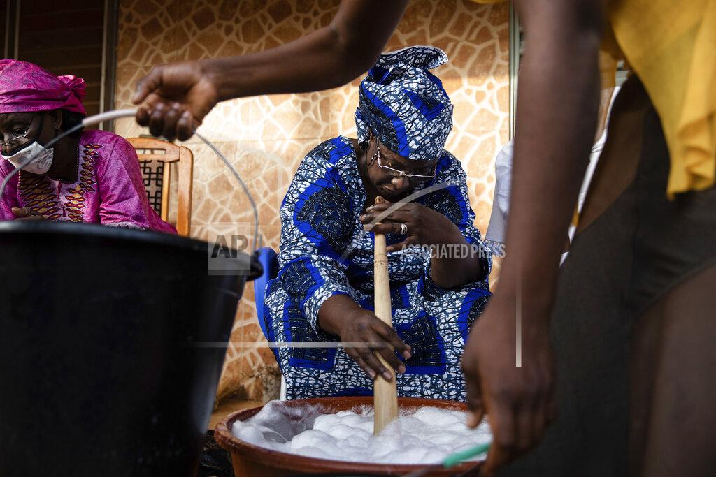 Sophie Garcia Women gather to make soap at Zenabou Coulibaly Zongo's house in Ouagadougou, Burkina Faso, Tuesday, Oct. 26, 2021. Zongo spends her own money making soap and buying hand sanitizer for mosques, markets and health centers. At the start of the pandemic, Zongo, now 63, was hospitalized with bronchial pneumonia. She paid out of pocket for two weeks' worth of oxygen treatments at a private clinic, where she watched others die from respiratory problems. (AP Photo/Sophie Garcia)