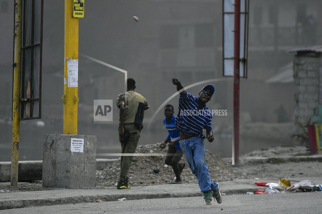 Matias Delacroix A protester demanding justice for the assassinated President Jovenel Moise hurls a stone in Cap-Haitien, Haiti, Thursday, July 22, 2021. Demonstrations after a memorial service for Moise turned violent on Thursday afternoon with protesters shooting into the air, throwing rocks and overturning heavy concrete barricades next to the seashore as businesses closed and people took cover. (AP Photo/Matias Delacroix)