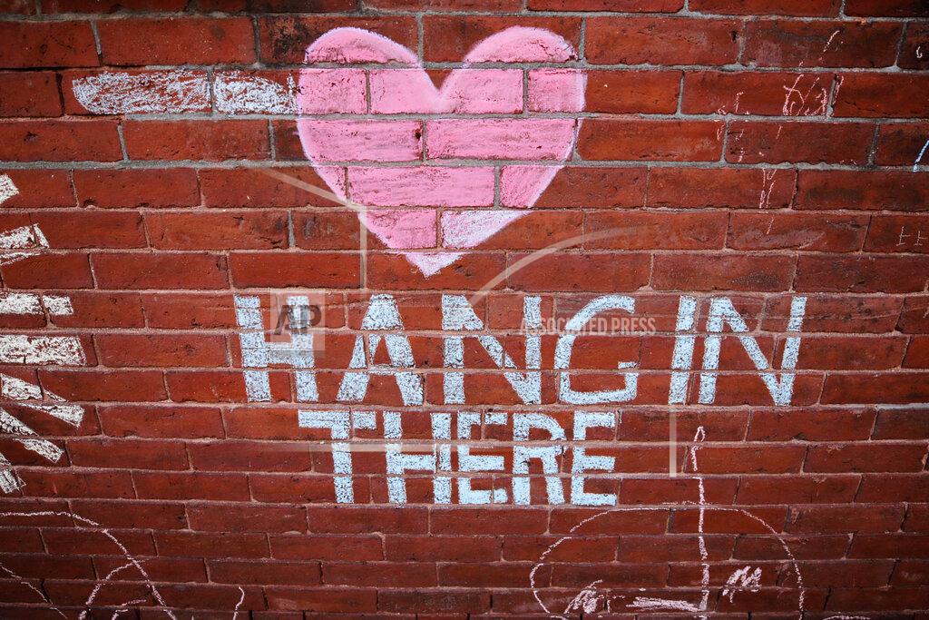 A heart and the words "Hang in There" adorn the wall of an alleyway, sharing an inspirational message, outside the Cravings Cafe and Gift Shop in Nashua, N.H., Wednesday, May 27, 2020. Many of the adults with disabilities that work at the cafe and gift shop have not been able to go to their usual jobs at the shop due to the COVID-19 virus outbreak. (AP Photo/Charles Krupa)