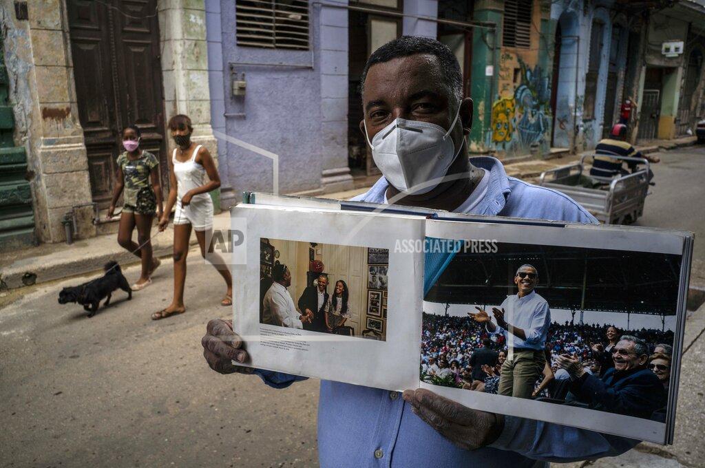Ramon Espinosa FILE - In this Oct. 22, 2020 file photo wearing a face mask amid the new coronavirus pandemic, Cristobal Marquez, owner of "Cristobal's," the restaurant where Michelle and Barak Obama had lunch during their visit to Cuba in 2016, shows the book made by White House photographer Pete Souza, in Havana, Cuba. While Joe Biden was part of an administration that reestablished diplomatic ties with Cuba, loosened travel restrictions and made it easier for Cubans in the United States to send money home, President Donald Trump has increased sanctions on companies that do business with the island's government and even banned Americans from staying in Cuban state-owned hotels. (AP Photo/Ramon Espinosa, File)