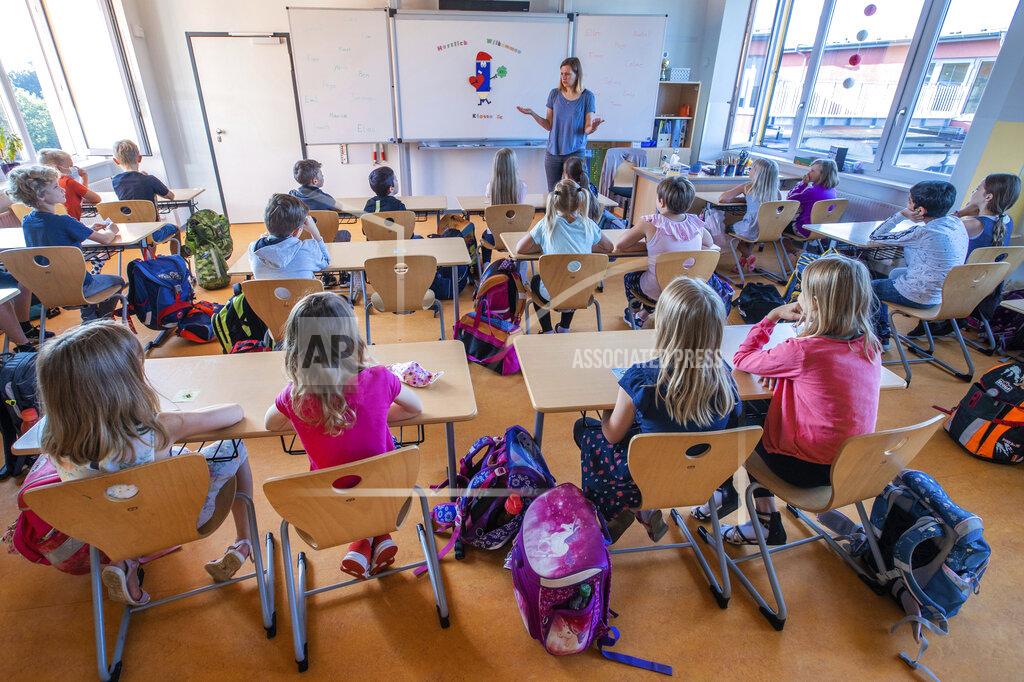 Jens Buettner FILE - In this Monday, Aug. 3, 2020 file photo, teacher Francie Keller welcomes the pupils of class 3c of the Lankow primary school on their first school day after the summer holidays in Schwerin, Germany. Despite a spike in virus infections, European authorities are determined to send children back to school. (Jens Buettner/DPA via AP, file)
