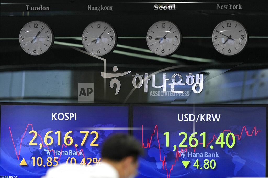 Lee Jin-Man A currency trader walks near the screens showing the Korea Composite Stock Price Index (KOSPI), left, and the foreign exchange rate between U.S. dollar and South Korean won in Seoul, South Korea, Wednesday, May 25, 2022. Asian stock markets were mixed Wednesday after Wall Street sank on weak U.S. housing sales and a profit warning by a prominent social media brand. (AP Photo/Lee Jin-man)