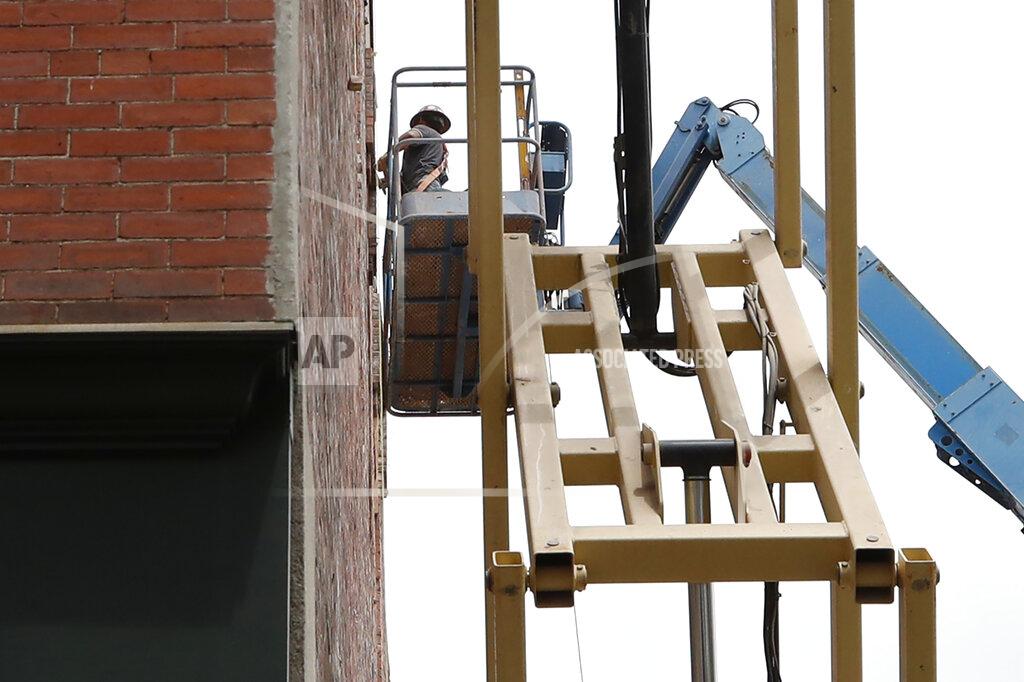 Elise Amendola A man on a crane works to fix a building facade, Friday, June 5, 2020, in Lawrence, Mass. The U.S. unemployment rate fell unexpectedly in May to 13.3% — still on par with what the nation witnessed during the Great Depression — as states loosened their coronavirus lockdowns and businesses began recalling workers. (AP Photo/Elise Amendola)