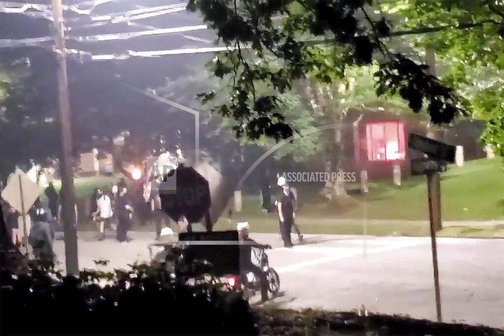 The building, seen right in the background, that houses Georgia State Patrol headquarters is vandalized in Atlanta, Sunday, July 5, 2020. Video showed protesters appearing to set off at least one firework inside the building. (Kimberly Krautter via AP)