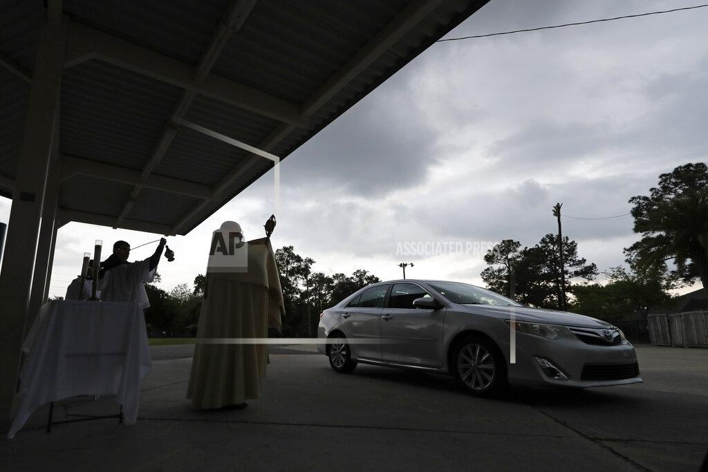 Gerald Herbert FILE - In this April 7, 2020 file photo, Fr. Steve Buno, Pastor of St. Rita of Cascia Catholic Church in Harahan, La., performs drive-thru Benediction of the Blessed Sacrament, as a form of social distancing due to the new coronavirus, during Holy Week. Where political divides marred early recovery efforts after Hurricane Katrina in 2005, Louisiana is showing rare political unity in the fight against the new coronavirus. (AP Photo/Gerald Herbert, File)