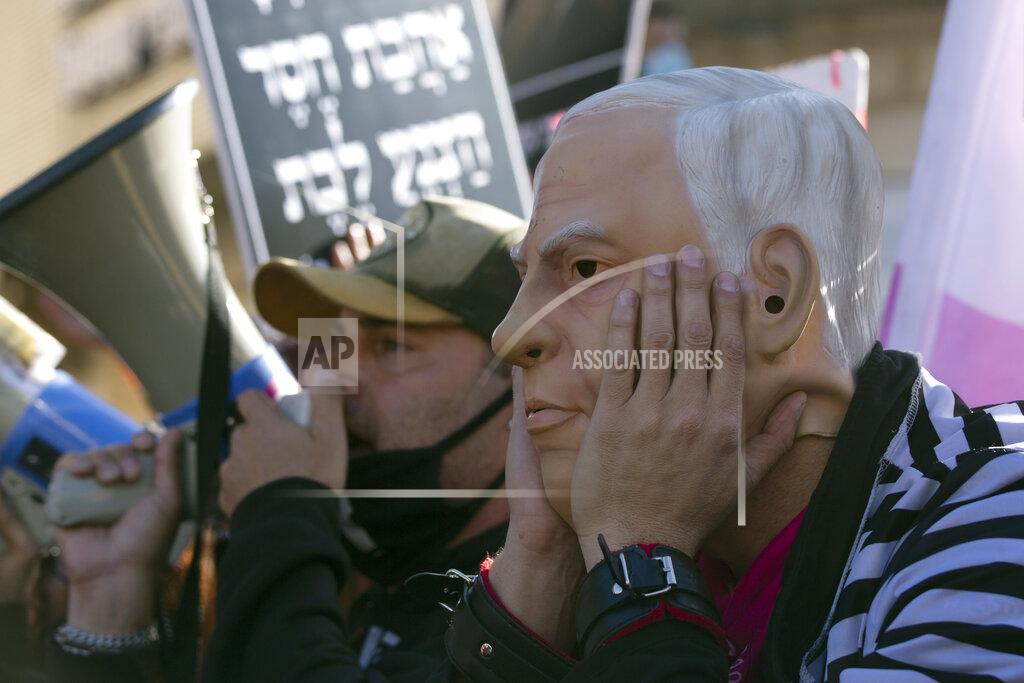 Maya Alleruzzo Protesters, including one wearing a rubber mask depicting Israeli Prime Minister Benjamin Netanyahu gather outside of the District Court during his corruption trial in Jerusalem, Monday, Feb. 8, 2021. Netanyahu has pleaded not guilty as his trial on corruption charges resumes in a Jerusalem courtroom just weeks before national elections in which he hopes to extend his 12-year rule. (AP Photo/Maya Alleruzzo)