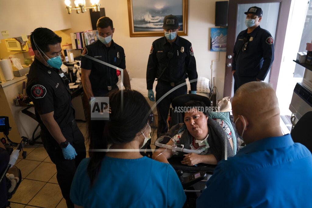 Jae C. Hong Socorro Franco-Martinez, seated, who has muscular dystrophy, is surrounded by Torrance firefighters as she talks with pharmacist Stella Kim, foreground left, after getting her second dose of the Pfizer COVID-19 vaccine in her apartment, Wednesday, May 12, 2021, in Torrance, Calif. Teamed up with the Torrance Fire Department, Torrance Memorial Medical Center started inoculating people at home in March, identifying people through a city hotline, county health department, senior centers and doctor's offices, said Mei Tsai, the pharmacist who coordinates the program. (AP Photo/Jae C. Hong)