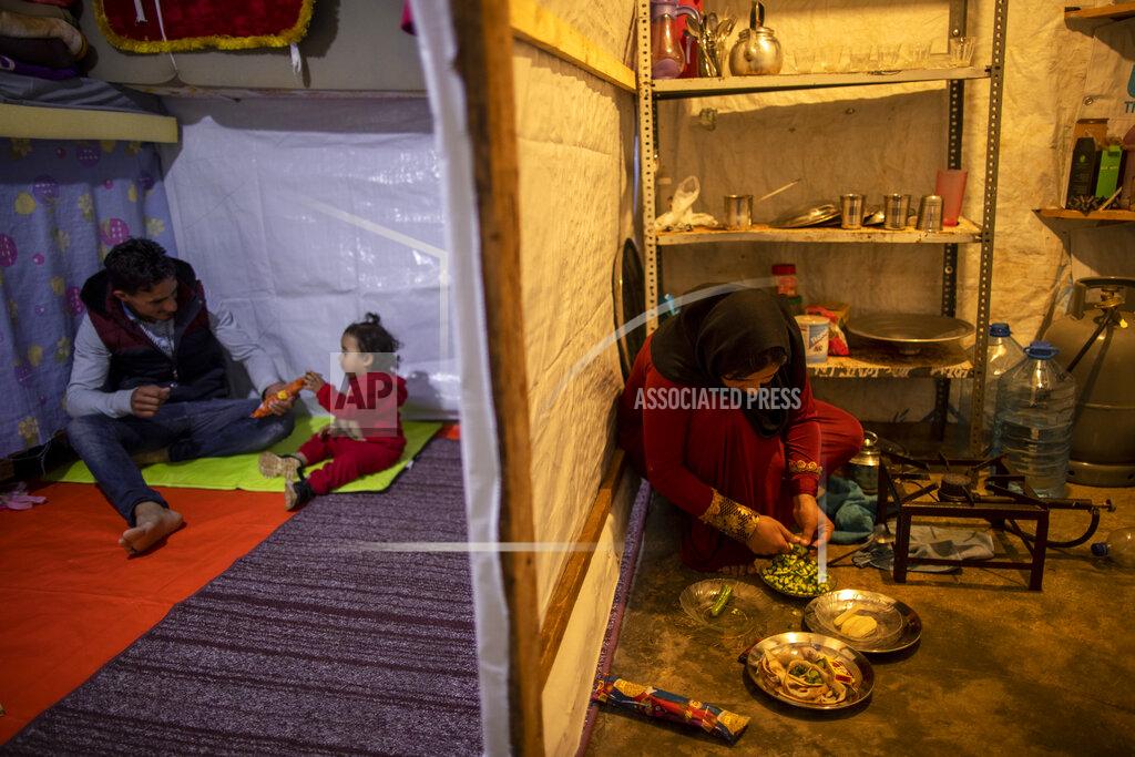 Hassan Ammar Syrian refugee Ayesha al-Abed, 21, right, prepares food as her Husband Raed Mattar, 24, left, plays with their daughter Rayan, 18 months old, before they break their fast on the first day of fasting month of Ramadan, at an informal refugee camp, in the town of Bhannine in the northern city of Tripoli, Lebanon, Tuesday, April 13, 2021. For many Syrian refugee families in Lebanon, Ramadan comes as a hard life of displacement has gotten even harder after a pandemic year that deepened economic woes in their host country. (AP Photo/Hassan Ammar)