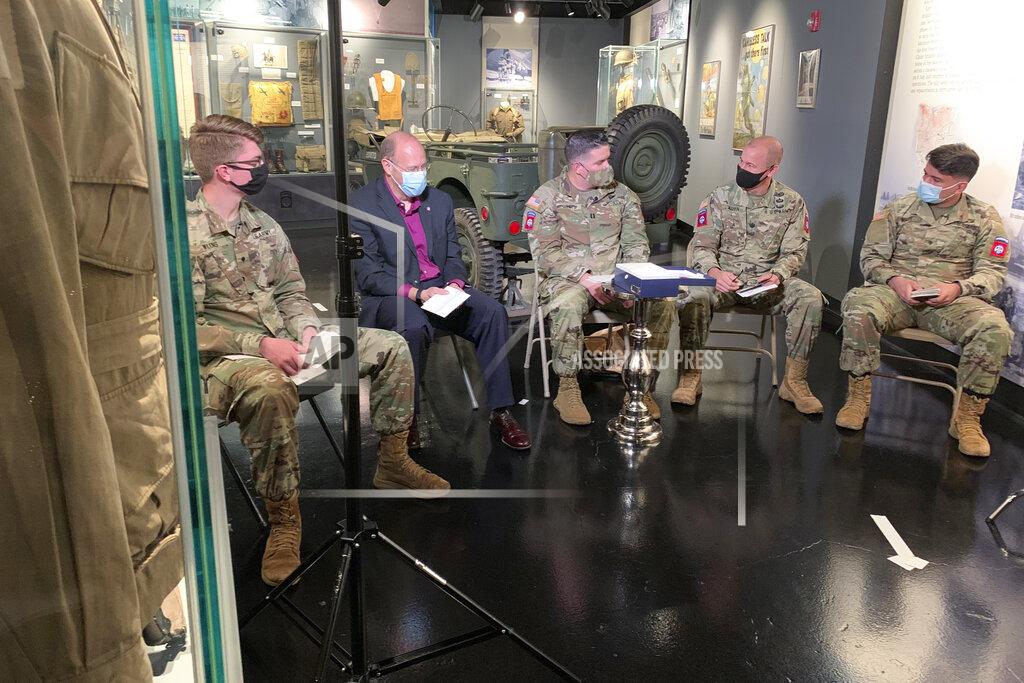 In this Tuesday, December 15, 2020 photo, 82nd Airborne Division paratroopers and historian John Aarsen, second from left, read through post cards sent by the town of Sainte-Mere-Eglise, France. Over 500 notes were penned for U.S. soldiers after their trip commemorating the anniversary of D-Day was cancelled amid the coronavirus pandemic. (AP Photo/Sarah Blake Morgan) (AP Photo/Sarah Blake Morgan)