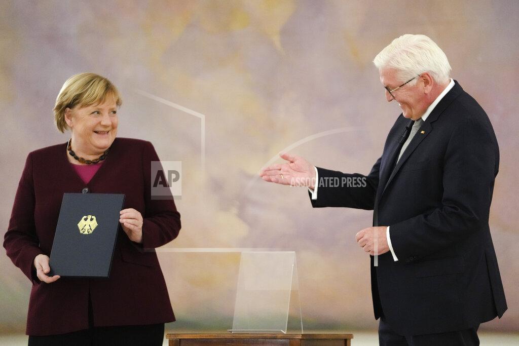 Markus Schreiber German Chancellor Angela Merkel, left receives her certificate of dismissal from German President Frank-Walter Steinmeier in Berlin, Tuesday, Oct. 26, 2021. Merkel stays in office until a successor is elected. (AP Photo/Markus Schreiber)