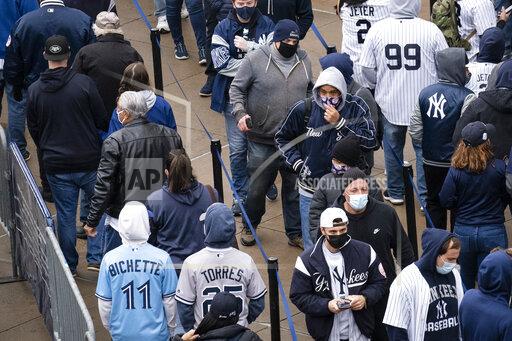 Spectators wait on a security line outside Yankee Stadium before an opening day baseball game against the Toronto Blue Jays, Thursday, April 1, 2021, in the Bronx borough of New York. Fans are back at the ballpark in limited numbers after they were shut out completely during the regular season last year due to the COVID-19 pandemic.(AP Photo/John Minchillo)