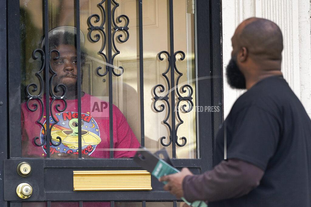 Paul Sancya Anthony Brinson, right, talks with a resident while leaving a flyer at a home in Detroit, Tuesday, May 4, 2021. Officials are walking door-to-door to encourage residents of the majority Black city to get vaccinated against COVID-19 as the city's immunization rate lags well behind the rest of Michigan and the United States. (AP Photo/Paul Sancya)