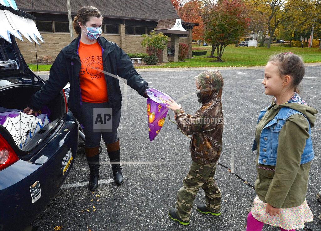 Jack Hanrahan Samantha Ruiz-Bueno, left, passes out candy to Boaz Pettis, 6, of Millcreek Township, Pa., and his sister Callista Pettis, 8, during the Drive-thru Trunk or Treat event for kids at the Fairview United Methodist Church, Saturday, Oct. 31, 2020, in Fairview, Pa. (Jack Hanrahan/Erie Times-News via AP)