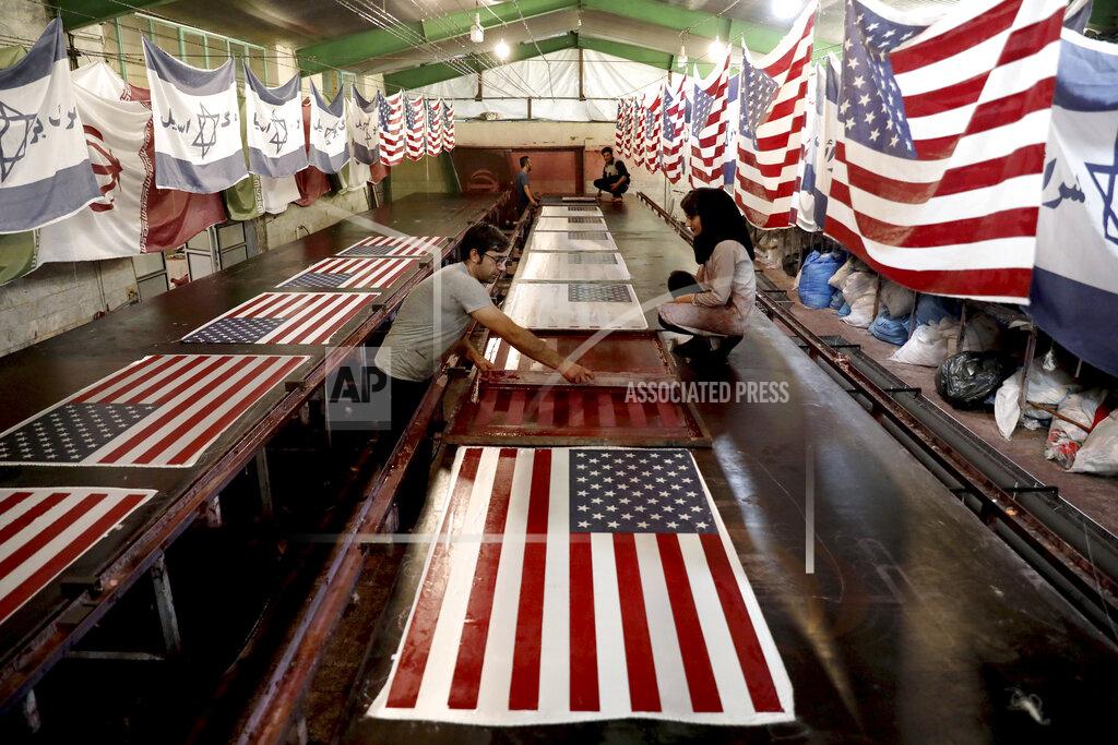 Ebrahim Noroozi FILE - In this Saturday, Feb. 8, 2020 file photo, workers print U.S. flags using a silkscreen, at the Diba Parcham Khomein factory in Heshmatieh village, a suburb of Khomein city, in central Iran. In Iran, everything feels up in the air ahead of the U.S. election. Currency markets have frozen awaiting the vote, though the damage has been done already by President Donald Trump's maximum pressure sanctions campaign. (AP Photo/Ebrahim Noroozi, File)