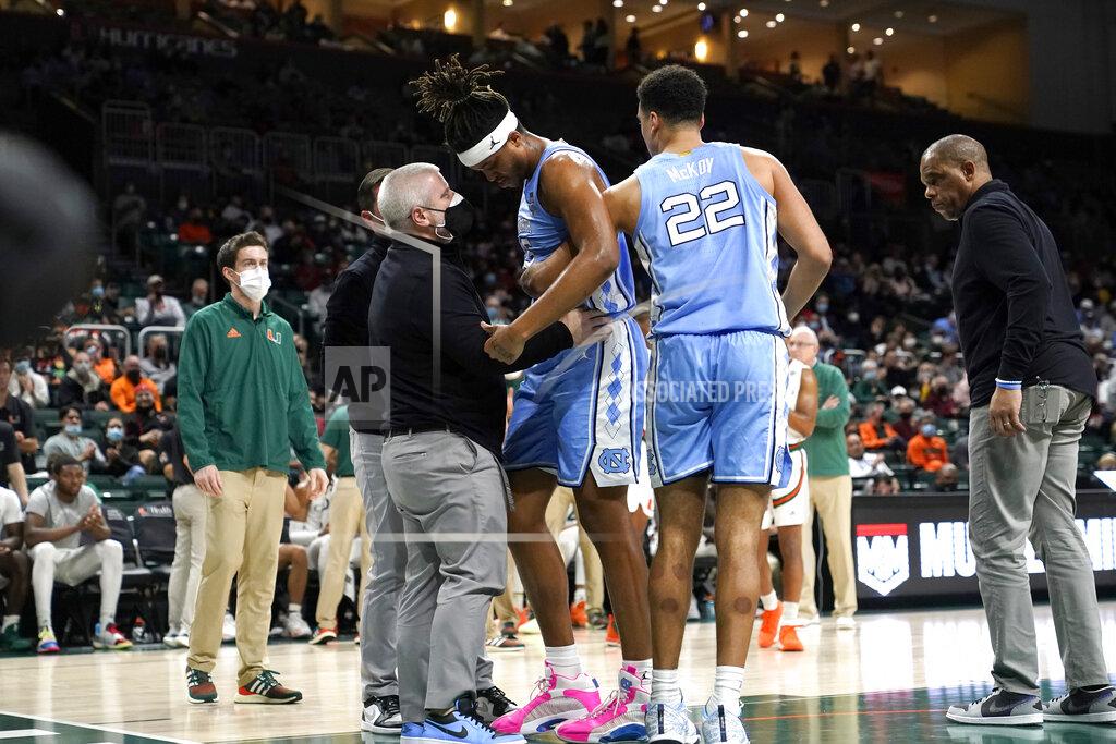 Lynne Sladky North Carolina forward Armando Bacot, center, is helped up off the floor by forward Justin McKoy (22) as head coach Hubert Davis, right, looks on during the second half of an NCAA college basketball game against Miami, Tuesday, Jan. 18, 2022, in Coral Gables, Fla. Miami won 85-57. (AP Photo/Lynne Sladky)