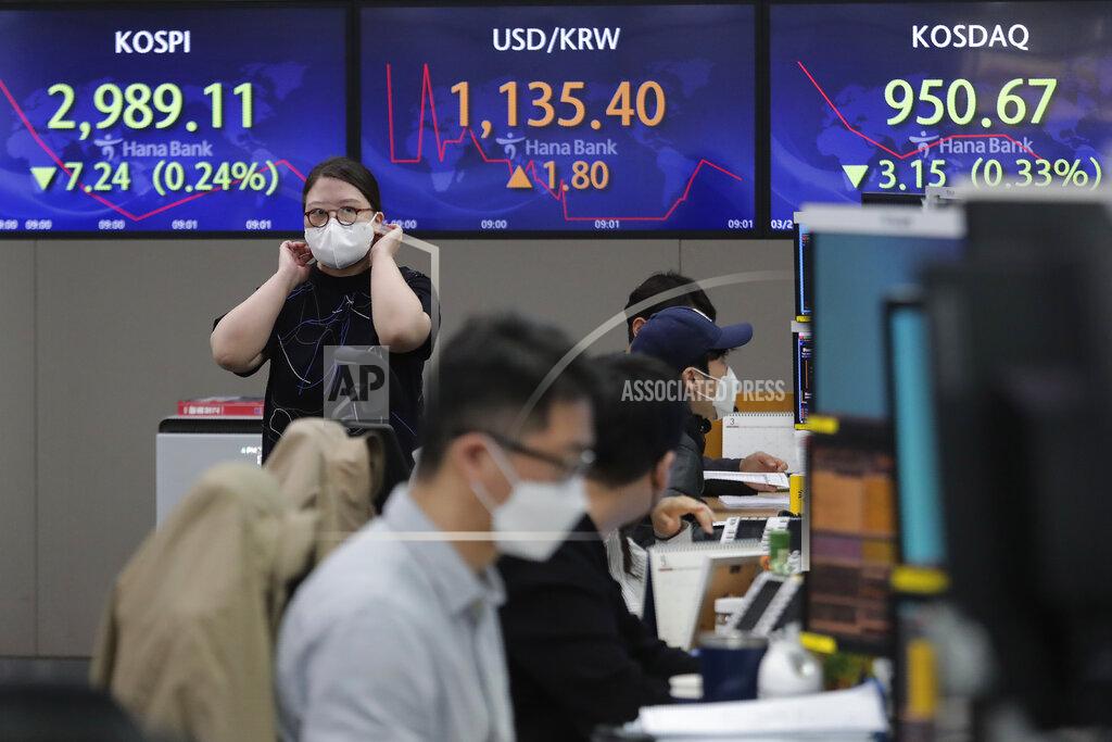 Ahn Young-Joon A currency trader passes by screens showing the Korea Composite Stock Price Index (KOSPI), left, and the foreign exchange rate between U.S. dollar and South Korean won, center, at the foreign exchange dealing room of the KEB Hana Bank headquarters in Seoul, South Korea, Thursday, March 25, 2021. Shares advanced in Asia on Thursday after a broad decline on Wall Street led by selling of tech heavyweights like Facebook and Apple. (AP Photo/Ahn Young-joon)