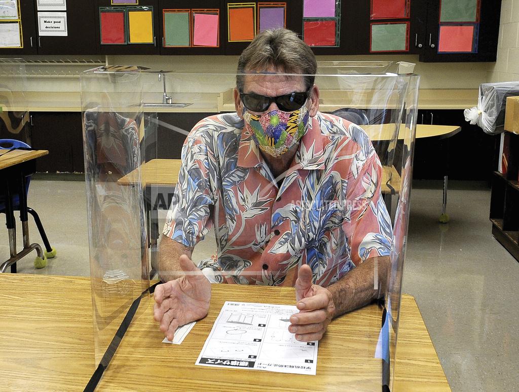 Laura Ruminski Kahakai Elementary School Principal James Denight demonstrates what a social distancing classroom with desk shields will look like for the upcoming school year, in Kailua-Kona, Hawaii, date not known. While Hawaii has one of the lowest rates of cases per capita in the country and many of its schools have open-air campuses, the challenges of returning kids full time to classrooms may still be insurmountable. (Laura Ruminski/West Hawaii Today via AP)