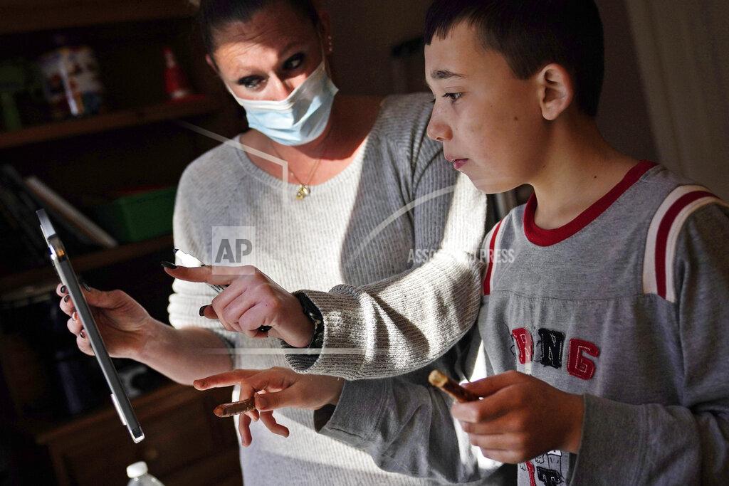 Seth Wenig FILE — in this Nov. 18, 2020 file photo, paraprofessional Jessica Wein helps Josh Nazzaro answer questions from his teacher while attending class virtually from his home in Wharton, N.J. Parents of schoolchildren learning from home shouldn't necessarily count on reclaiming the dining room table any time soon. After seeing two academic years thrown off course by the pandemic, school leaders around the country are planning for the possibility of more distance learning next fall at the start of yet another school year. (AP Photo/Seth Wenig, File)