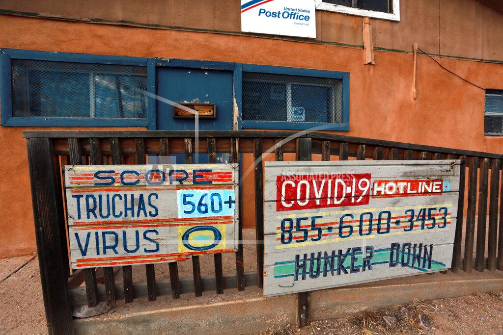 Cedar Attanasio In this Sunday, Aug. 9, 2020, photo, a hand-painted sign at a post office keeps score of the COVID-19 cases and deaths in the village of Truchas, New Mexico. Nearby wilderness areas and logging roads have allowed residents to hunker down with family cookouts and outdoor recreation. (AP Photo/Cedar Attanasio)