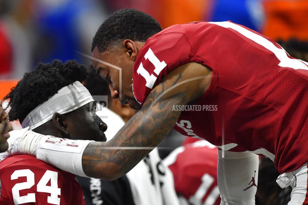 John Amis Oklahoma wide receiver Jadon Haselwood (11) speaks with Oklahoma running back Marcus Major (24) during the second half of the Peach Bowl NCAA semifinal college football playoff game against LSU, Saturday, Dec. 28, 2019, in Atlanta. LSU won 63-28. (AP Photo/John Amis)