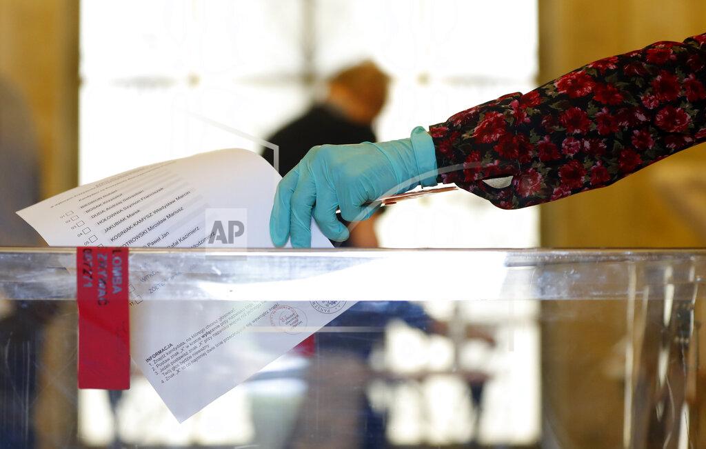 Petr David Josek A resident, wearing protective gloves, casts a vote during presidential election in Warsaw, Poland, Sunday, June 28, 2020. The election will test the popularity of incumbent President Andrzej Duda who is seeking a second term and of the conservative ruling party that backs him. (AP Photo/Petr David Josek)