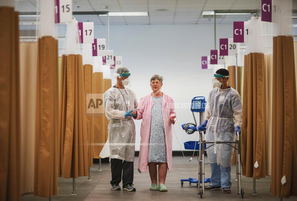 David Goldman COVID-19 patient Kathleen Feeney, 79, works with physical therapist Chris Collard, left, and registered nurse Edward Rojas at a field hospital operated by Care New England set up in a former bank call center to handle a surge of COVID-19 patients in Cranston, R.I, Monday, Dec. 28, 2020. Kent Field Hospital opened on Nov. 30, just before Rhode Island's infection rate became the highest in the world. Kent was using all its beds for its sickest COVID-19 patients, and needed somewhere for the overflow. (AP Photo/David Goldman)