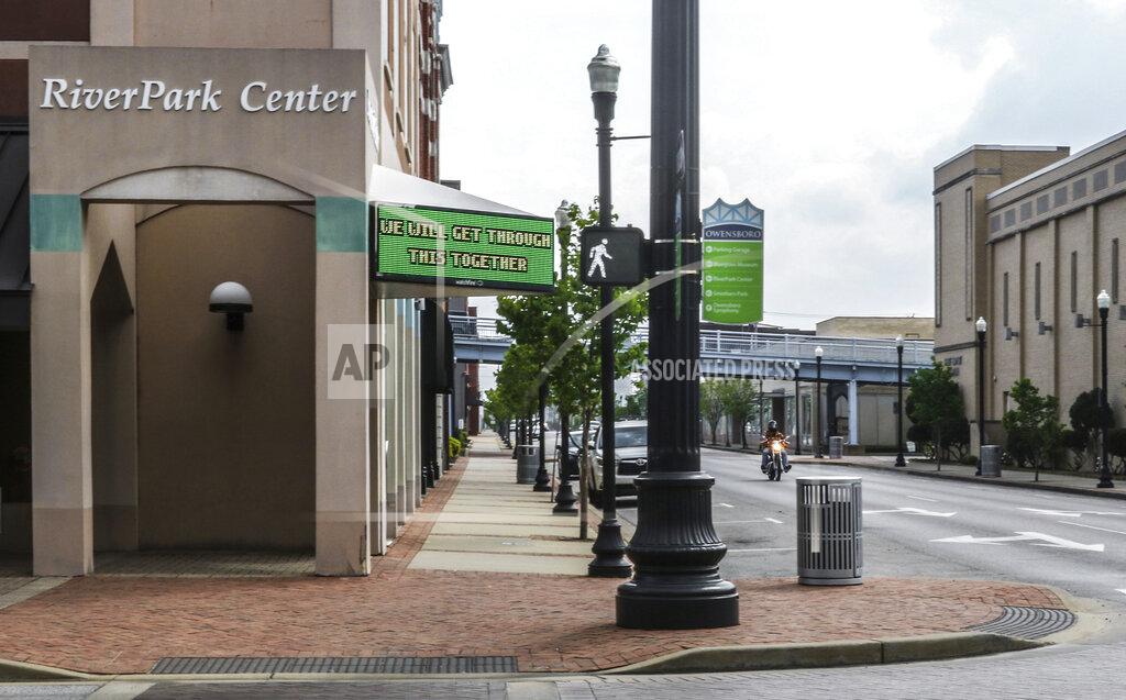A motorcyclist cruises down a deserted E. Second Street past the Owensboro RiverPark Center, where a sign that normally posts upcoming events reads "We will get through this together," as most businesses in the downtown area have closed up shop due to the coronavirus pandemic, Wednesday, April 8, 2020, in Owensboro, Ky. (Greg Eans/The Messenger-Inquirer via AP)