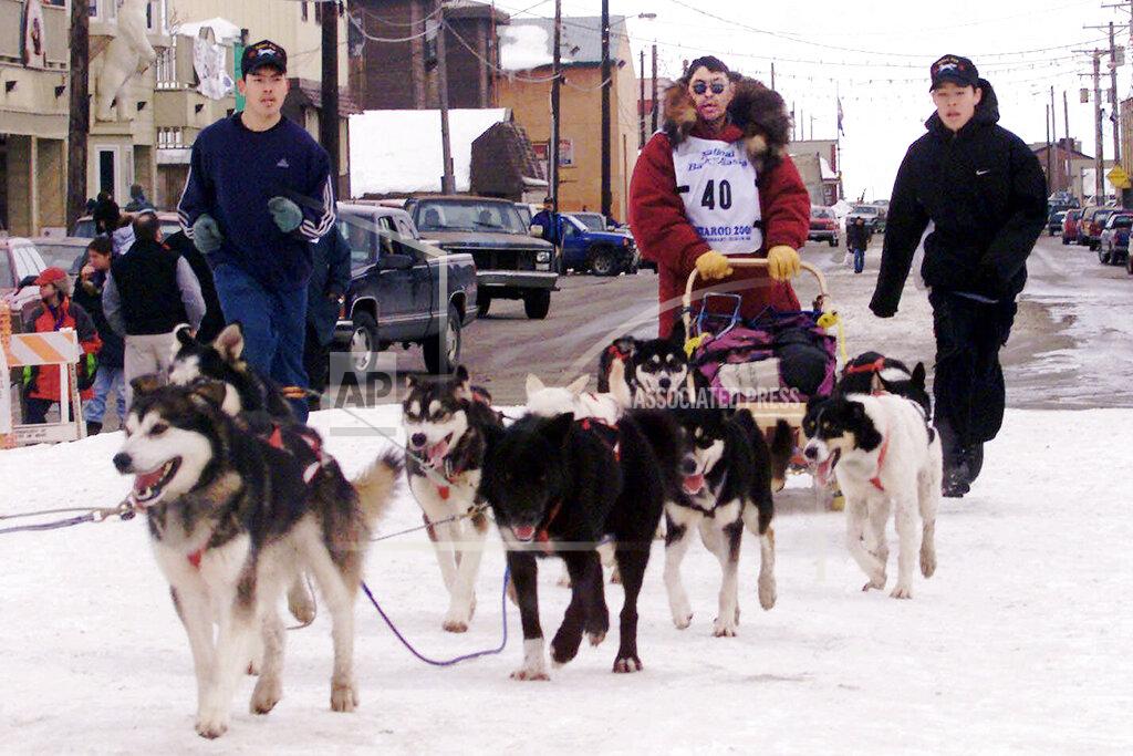 Al Grillo FILE - In this March 17, 2000, file photo, Emmitt Peters, center, is followed by his sons Emmitt Jr., left, and Emory as he drives his team up the finish chute of the Iditarod Trail Sled Dog Race in Nome, Alaska. Alaska State Troopers confirm Peters, nicknamed the "Yukon Fox," died Thursday, April 2, 2020, at his home in Ruby, Alaska. (AP Photo/Al Grillo, File)