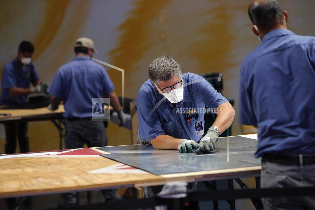 Gerald Herbert Workers use a stencil to cut material as they manufacture personal protection equipment for hospitals, on the Louisiana State University campus, in response to the coronavirus pandemic, in Baton Rouge, La., Friday, April 17, 2020. (AP Photo/Gerald Herbert)