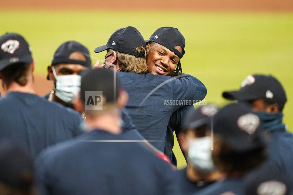 Brynn Anderson Atlanta Braves' Ronald Acuna Jr. center, hugs a coach to celebrate after a baseball game to clinch the NL East baseball title against the Miami Marlins on Tuesday, Sept. 22, 2020, in Atlanta. (AP Photo/Brynn Anderson)