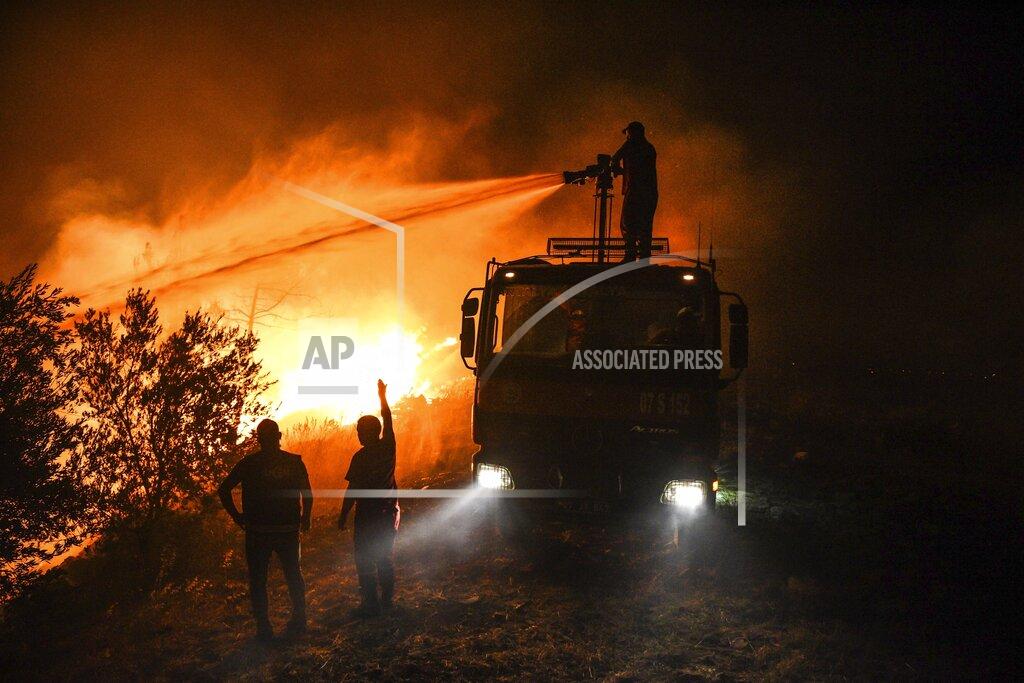 Uncredited Firefighters pour water as they try to get the fire under control in Kirli village near the town of Manavgat, in Antalya province, Turkey, early Friday July 30, 2021. The fire that continued all night could not be brought under control and people living in the village started to evacuate. Wildfires are common in Turkey's Mediterranean and Aegean regions during the arid summer months, although some previous forest fires have been blamed on arson. (AP Photo)