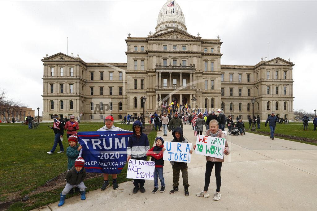 Paul Sancya Children pose for a photograph during a protest at the State Capitol in Lansing, Mich., Wednesday, April 15, 2020. Flag-waving, honking protesters drove past the Michigan Capitol on Wednesday to show their displeasure with Gov. Gretchen Whitmer's orders to keep people at home and businesses locked during the new coronavirus COVID-19 outbreak. (AP Photo/Paul Sancya)