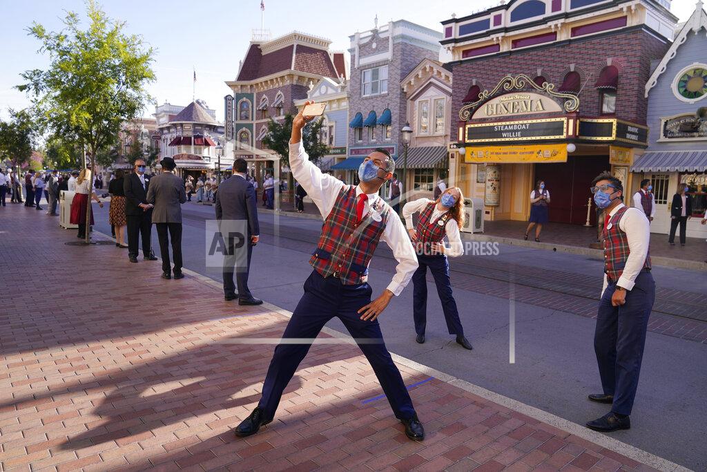 Jae Hong Employees take a photo on Main Street before the gates open at Disneyland in Anaheim, Calif., Friday, April 30, 2021. The iconic theme park in Southern California that was closed under the state's strict virus rules swung open its gates Friday and some visitors came in cheering and screaming with happiness. (AP Photo/Jae Hong)