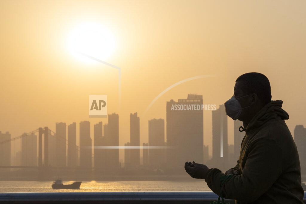 Ng Han Guan FILE - In this Jan. 15, 2021, file photo, a man wearing a mask is silhouetted as the sun sets along the riverbank in Wuhan in central China's Hubei province. Nearly a year to the day after Wuhan went into lockdown to contain a virus that had already escaped, President Joe Biden began putting into effect a new war plan for fighting the outbreak in the United States, Germany topped 50,000 deaths, and Britain closed in on 100,000. (AP Photo/Ng Han Guan)