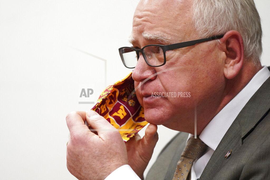 FILE - In this Jan. 26, 2021 file photo, Minnesota Gov. Tim Walz takes off his University of Minnesota cloth face mask to answer a question from a reporter during a press conference in St. Paul, Minn. Gov. Walz is quarantining for 10 days after being exposed to a staff member who tested positive for COVID-19, the governor's spokesman said Wednesday, March 17, 2021. (Anthony Souffle/Star Tribune via AP File)