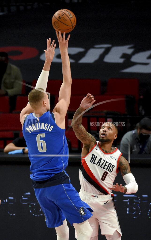 Steve Dykes Dallas Mavericks center Kristaps Porzingis, left, hits a shot over Portland Trail Blazers guard Damian Lillard during the first half of an NBA basketball game in Portland, Ore., Friday, March 19, 2021. AP Photo/Steve Dykes)