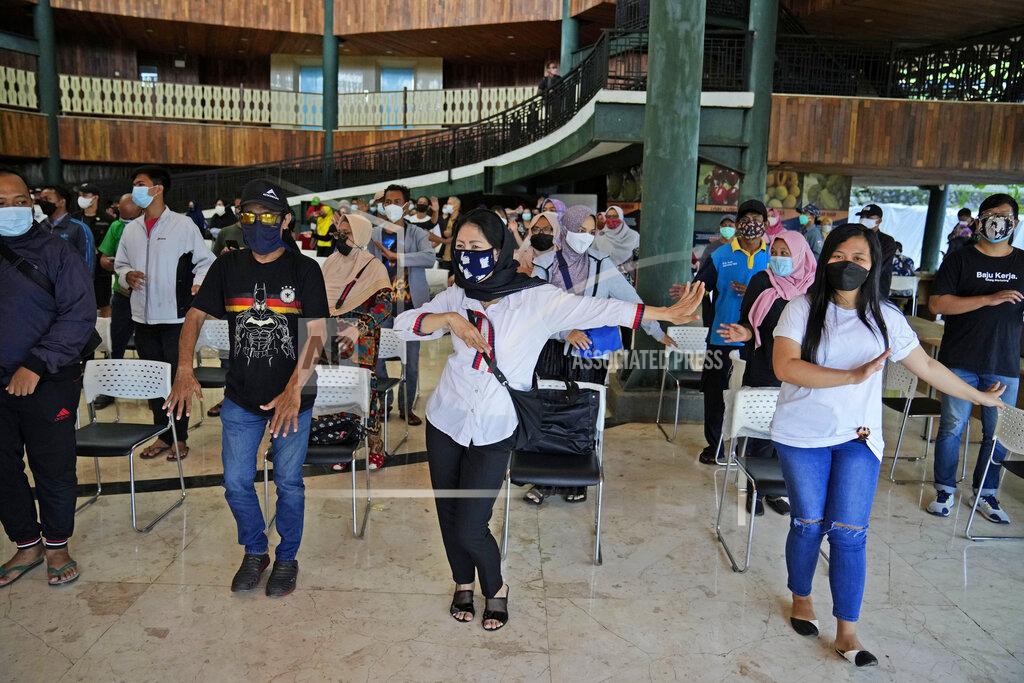 Dita Alangkara People dance to the music played by organizer while they wait to receive the Sinovac COVID-19 vaccine during a mass vaccination in Jakarta, Indonesia, Monday, June 21, 2021. Indonesia's president ordered authorities to speed up the country's vaccination campaign as the World Health Organization warned of the need to increase social restrictions in the country amid a fresh surge of coronavirus infections caused by worrisome variants. (AP Photo/Dita Alangkara)