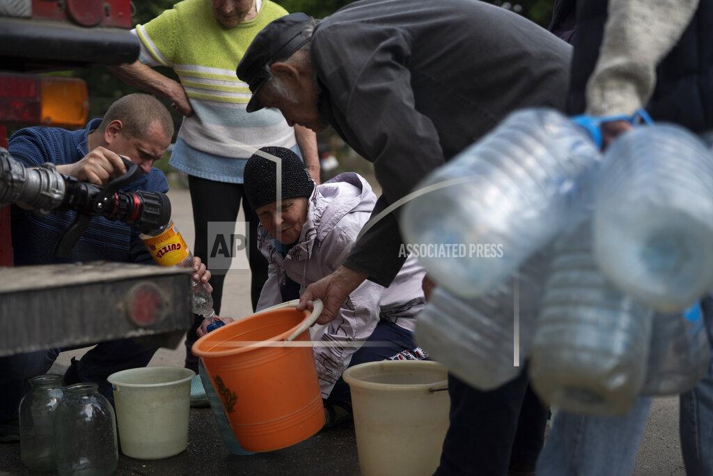 Leo Correa People gather to fill cans with water from a firefighters truck in Lysychansk, Luhansk region, Ukraine, Friday, May 13, 2022. (AP Photo/Leo Correa)