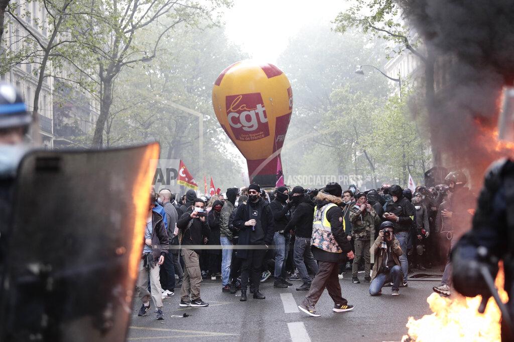 Lewis Joly Demonstrators watch riot police officers during May Day march scuffles Saturday, May 1, 2021 in Paris. Workers and union leaders dusted off bullhorns and flags that had stayed furled during coronavirus lockdowns for slimmed down but still boisterous May Day marches on Saturday, demanding more labor protections amid a pandemic that has turned economies and workplaces upside down. (AP Photo/Lewis Joly)