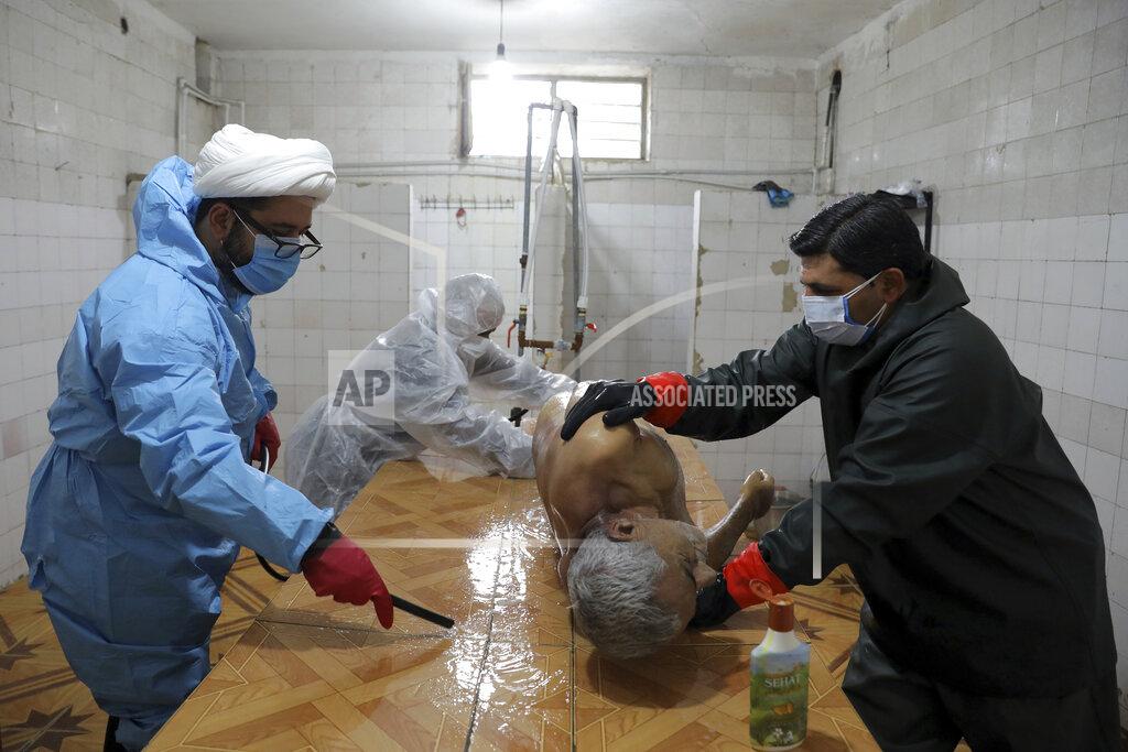 Volunteers wearing protective clothing prepare the body of a man who died from COVID-19 for a funeral at a cemetery in the outskirts of the city of Ghaemshahr, in northern Iran, Wednesday, Dec. 16, 2020. (AP Photo/Ebrahim Noroozi)